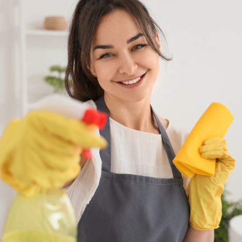 Personne souriante tenant des produits de nettoyage dans un environnement intérieur lumineux lié à l’entretien ménager  à Lac-Etchemin
